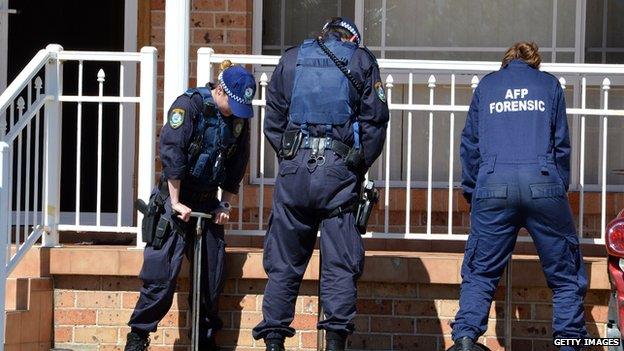 An Australian Federal Police forensic team examine the front yard of a house in Sydney