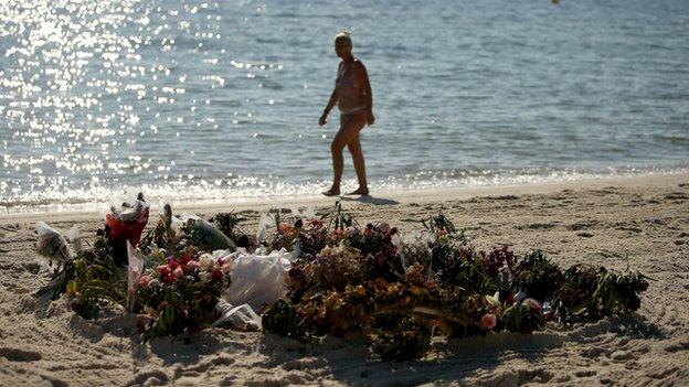 Tourist walks past flowers on Sousse beach