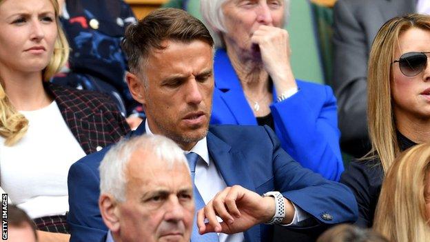 Phil Neville looks at his watch