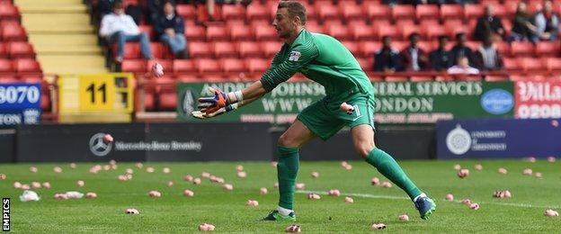 Charlton goalkeeper Declan Rudd tries to catch foam pigs thrown onto the pitch by fans