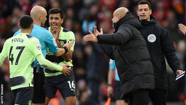 Guardiola and the City players surround Anthony Taylor