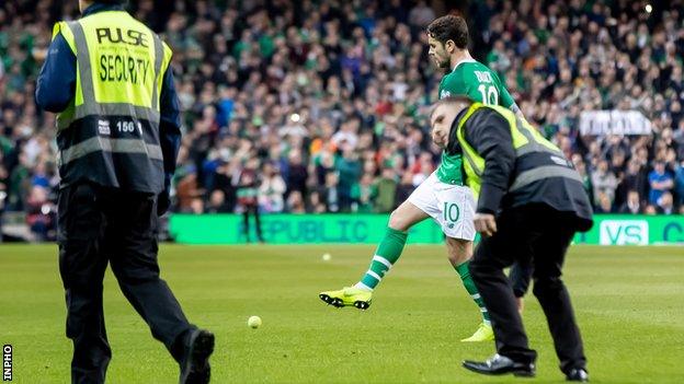 Stewards remove tennis balls from the pitch