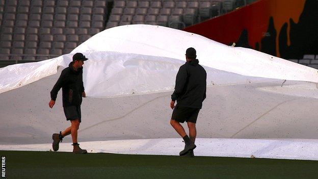 Groundstaff bring covers onto field