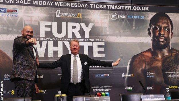 Tyson Fury poses with Frank Warren and a big picture of Diliian Whyte at a press conference