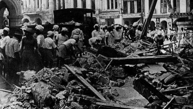 Workers in Singapore clear debris following bombing by Japan