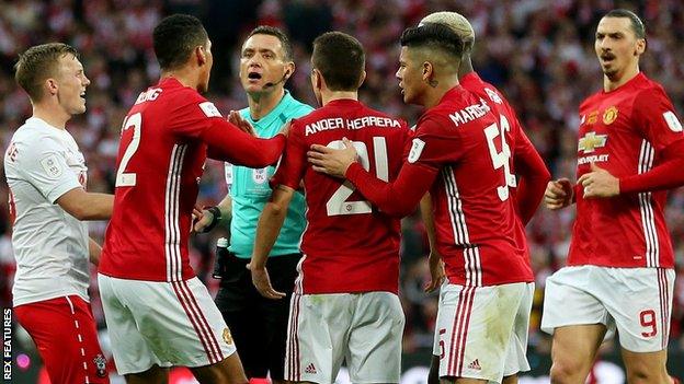 Man Utd players surround the referee