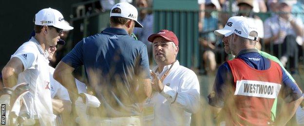 Officials explain to Dustin Johnson that he may be facing a penalty