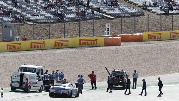 Race marshals inspect the drain covers on track