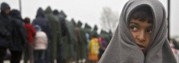 Migrant child covered in blanket stands in rain at Greek border camp near Idomeni, 10 March 2016