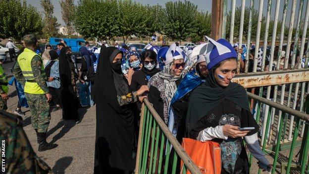 As Iranian female soccer fans enter the Azadi (Freedom) stadium in western Tehran, members of the special police force monitor the area