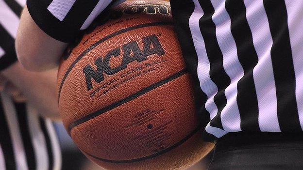 An official holds the ball during a US college basketball game