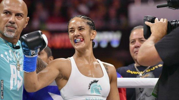 Amanda Serrano smiles with her coach standing beside her