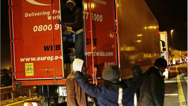 Migrants trying to board a lorry in traffic