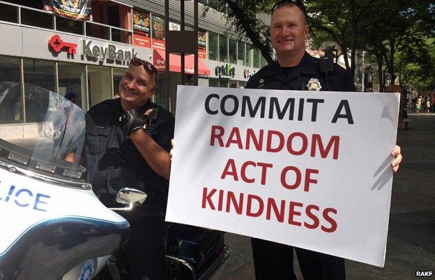 Police officers holding sign that reads "Commit a random act of kindness" - photo from Random Acts of Kindness Foundation