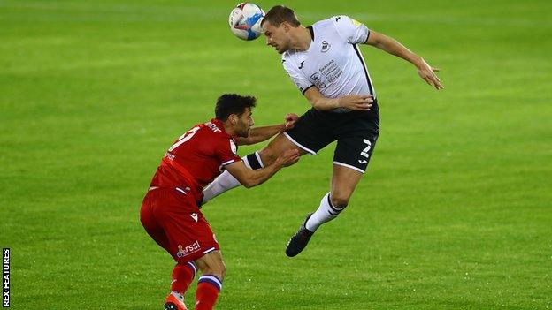 Ryan Bennett wins a header ahead of Sam Baldock