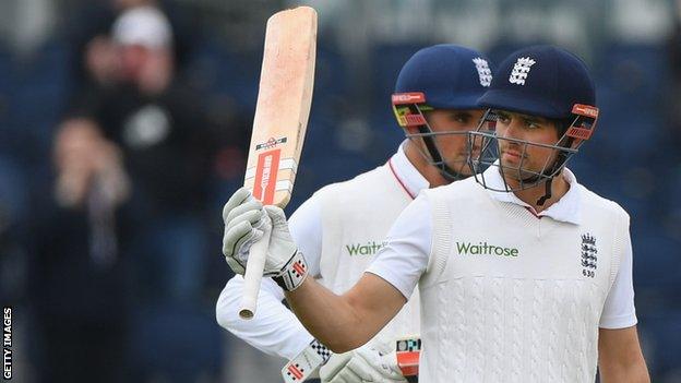 Alastair Cook raises his bat after reaching 10,000 Test runs