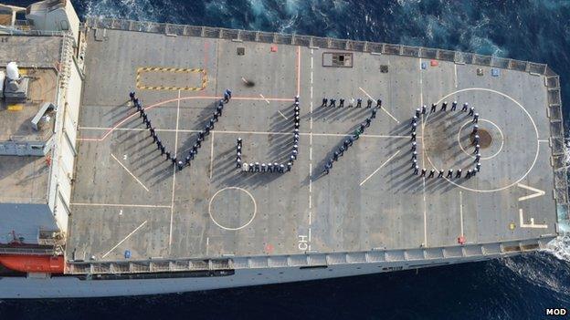 Sailors / crew of a Royal Navy supply ship spelling out "VJ70" on the flight deck of RFA Fort Victoria, while on operational duties in the Gulf