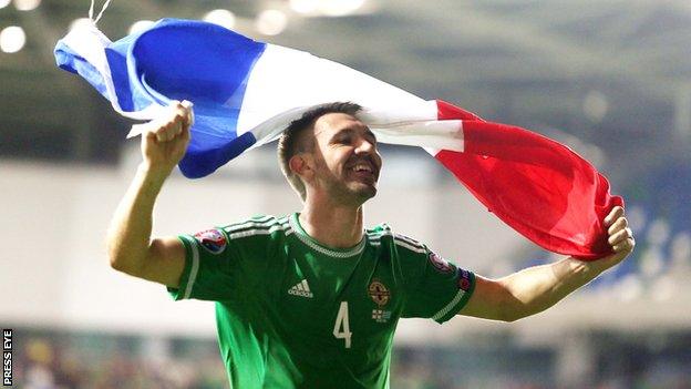 Defender Gareth McAuley celebrates with the French flag after NI beat Greece to qualify for Euro 2016