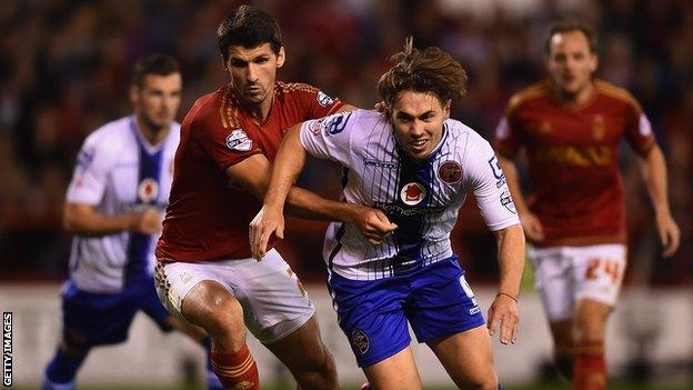 Walsall's hat-trick hero Tom Bradshaw holds off the challenge of Forest's Eric Lichaj