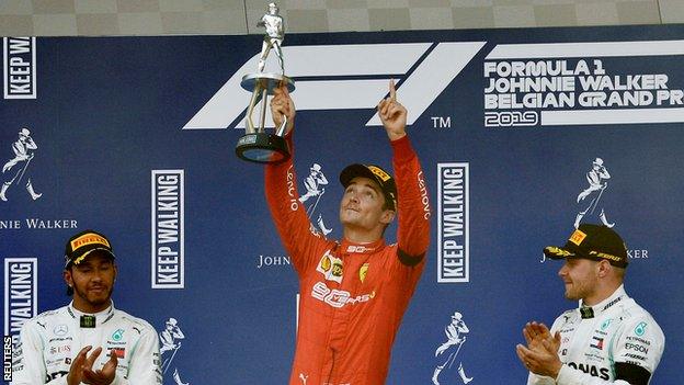 Hamilton and Bottas look on as Leclerc lifts the winner's trophy