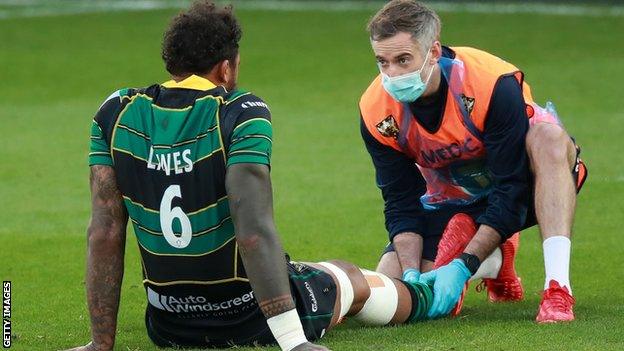 Courtney Lawes receives treatment on the pitch after being hurt against Sale