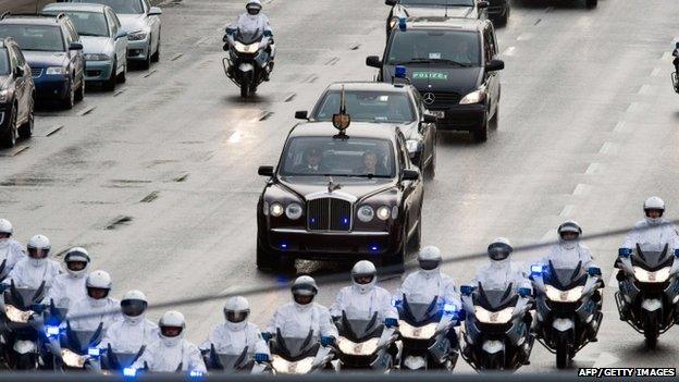 Police officers escort the limousine carrying the Queen