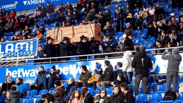 Alaves supporters dressed in black carrying a mock coffin in protest during their game against Levante