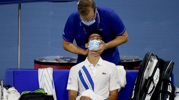 Novak Djokovic receives treatment on his neck