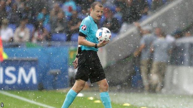 Czech referee Pavel Kralovec leads the players off the pitch after a hail storm