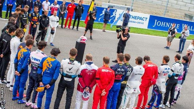 Formula 1 drivers gather around Anthoine Hubert's helmet