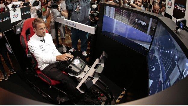 Jenson Button steers a race car stimulator in Singapore