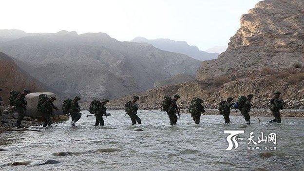 Chinese state media pictures show security forces searching a remote area of rugged terrain in Xinjiang