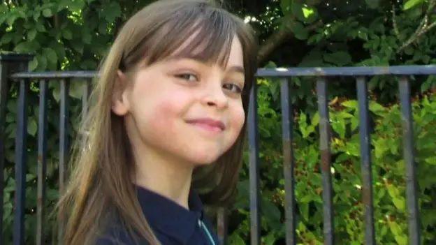 Saffie-Rose Roussos smiling for a picture next to some railings outside. 