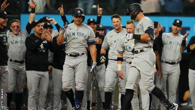 Aaron Judge is congratulated by his New York Yankees team-mates after hitting a record 62nd home run of the season