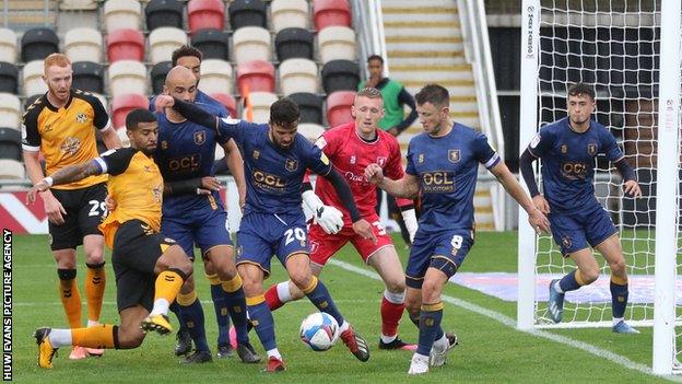 Stephen McLaughlin of Mansfield Town clears the ball as Joss Labadie of Newport County closes in
