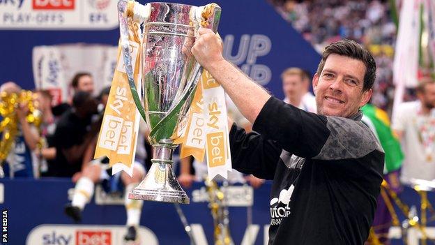 Port Vale boss Darrell Clarke holds the League Two play-off final trophy aloft after beating Mansfield Town