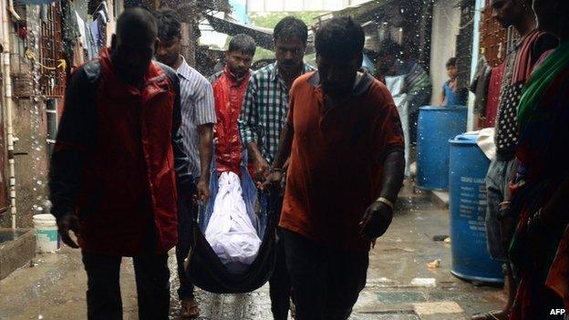 Indian family members carry the body of a victim of toxic home-made liquor consumption, during heavy rains in Mumbai on 20 June 2015.