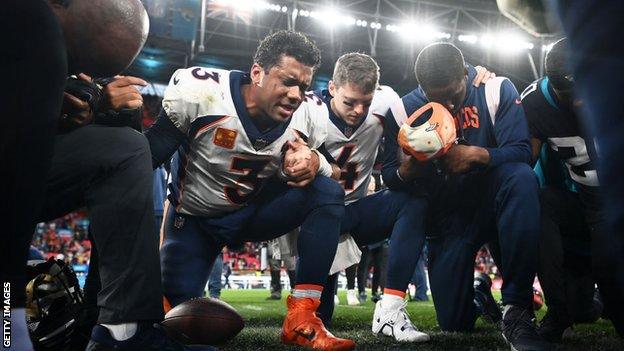 Russell Wilson praying with fellow players after a game at Wembley