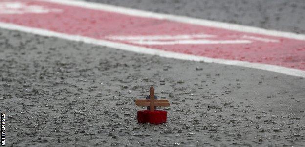 A paper boat floats in the pit lane as heavy rain delays the second practice