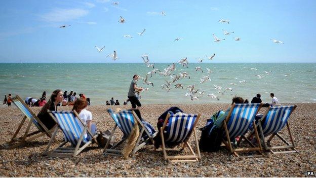 People in deck chairs on a beach