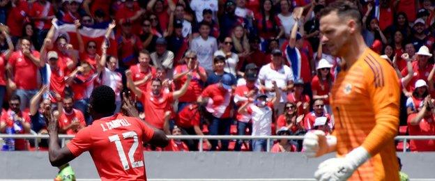 Joel Campbell wheels in celebration after scoring while there's disappointment for NI keeper Trevor Carson