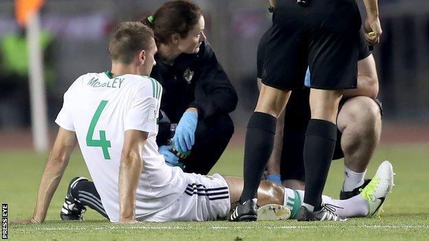 Gareth McAuley receives treatment before limping off in the Baku qualifier