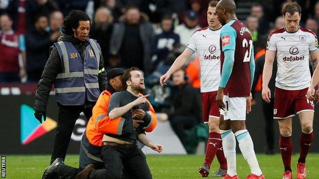 One of the fans who came on to the pitch during West Ham's defeat by Burnley is grabbed by a steward