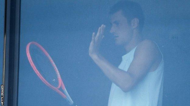 Bernard Tomic in a hotel room with a tennis racquet