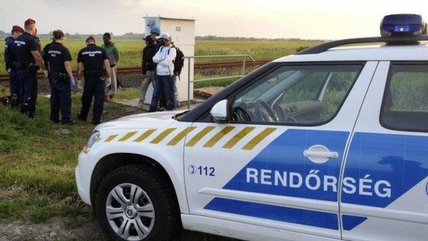 Migrants are detained by Hungarian police officers near Roszke, south of Szeged in Hungary, 21 May 2015.