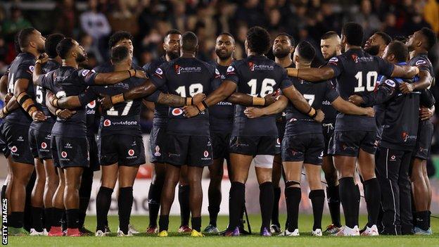 Fiji players sing a hymn after losing to England