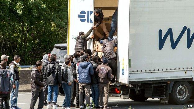 Migrants climb in the back of a lorry in Calais