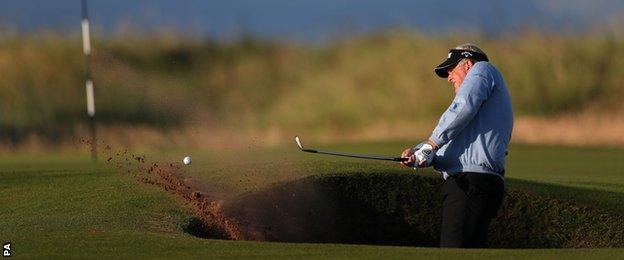 Colin Montgomerie hacks out the greenside bunker on the first hole