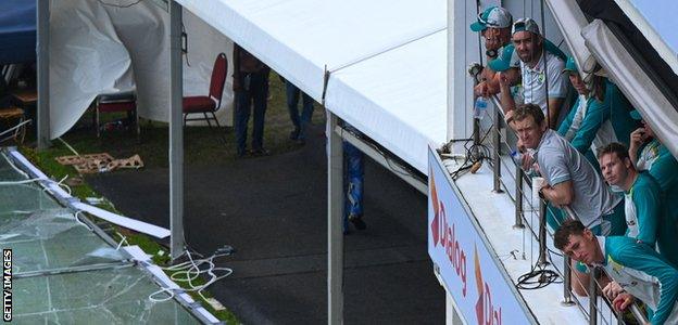 Australia players look on at the storm damage