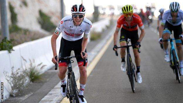 Tadej Pogacar out of his saddle, pursued by Adam Yates and other riders